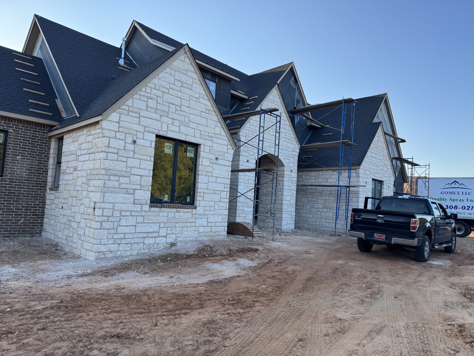 Project exterior showing dark brick paired with Austin white stone