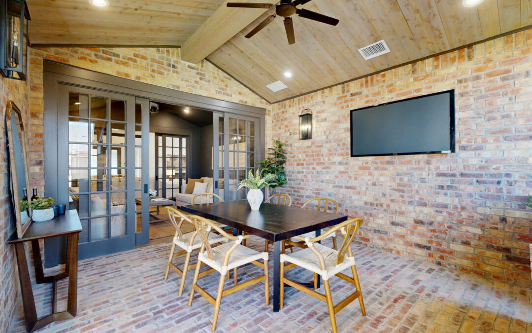 Country Bayou brick walls around a dining table beneath a wood-clad ceiling, with wide doors to an adjoining room.